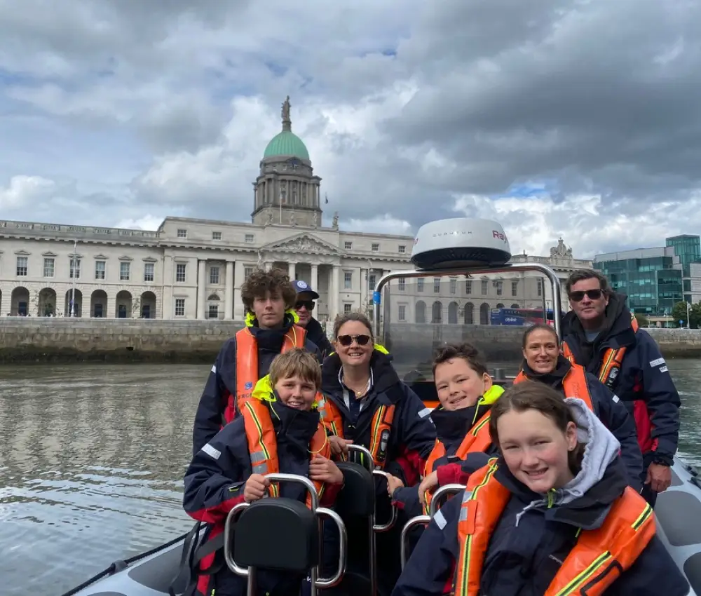 family enjoying a scenic boat tour in Dublin with calm waters and city views in the background