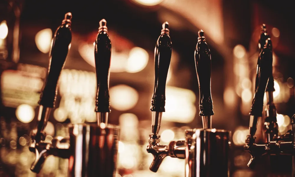 Close-up of beer taps in a warmly lit bar setting highlighting draft beer options