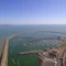 Aerial view of Dun Laoghaire Harbor showing two long piers enclosing numerous boats and yachts, with surrounding buildings and infrastructure under a clear blue sky