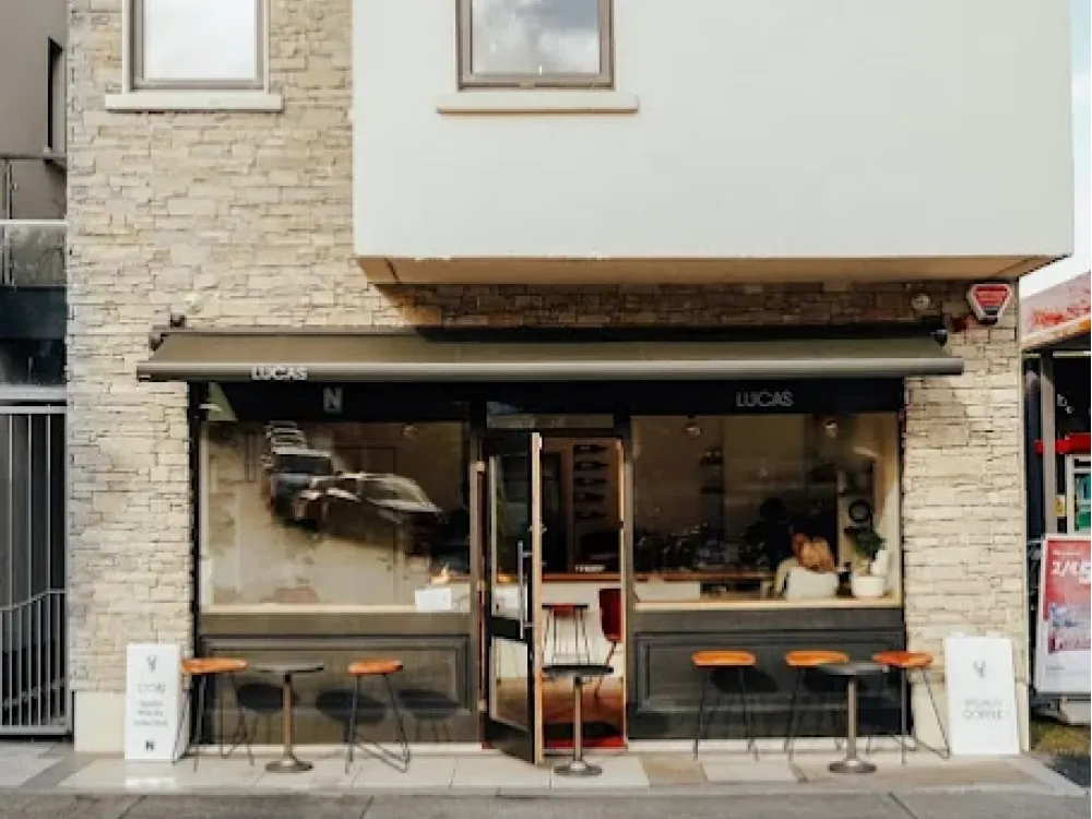 Exterior of LUCAS café with stone facade, large windows, outdoor seating